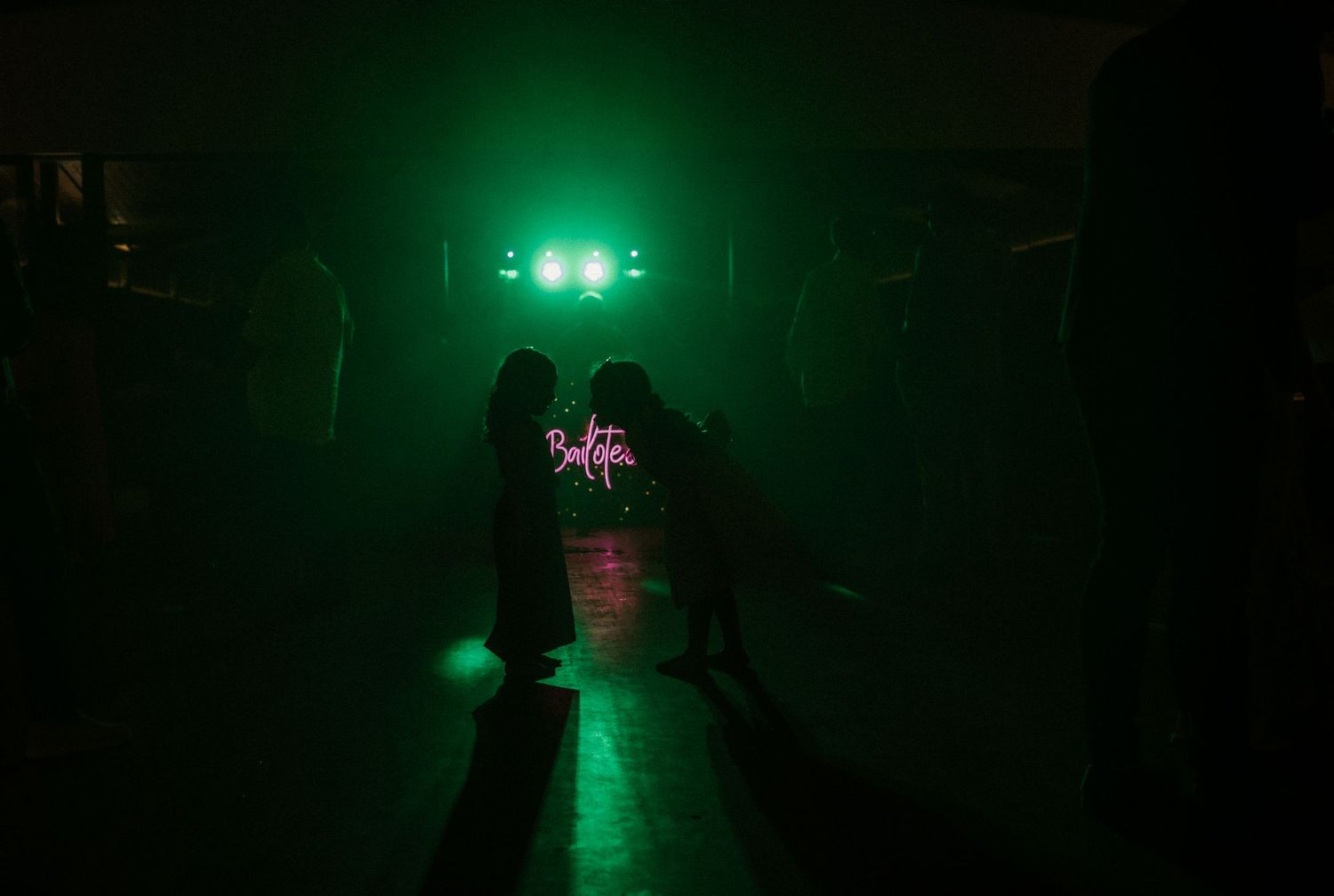Green laser beams illuminate a dark industrial space creating an eerie atmospheric effect.