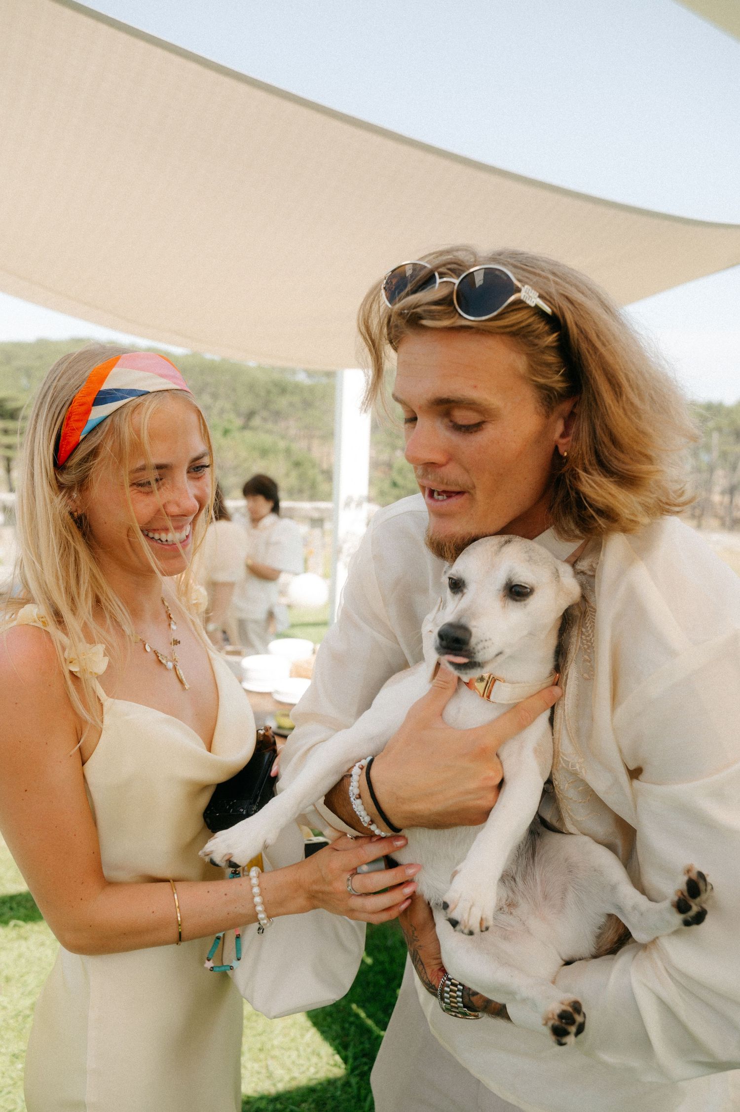 A series of candid photos showing joyful moments with a white dog at an outdoor event under a white tent.