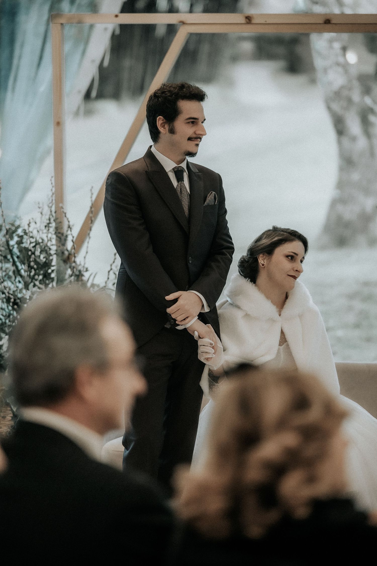 Wedding ceremony guests seated under a tent watching the proceedings unfold.