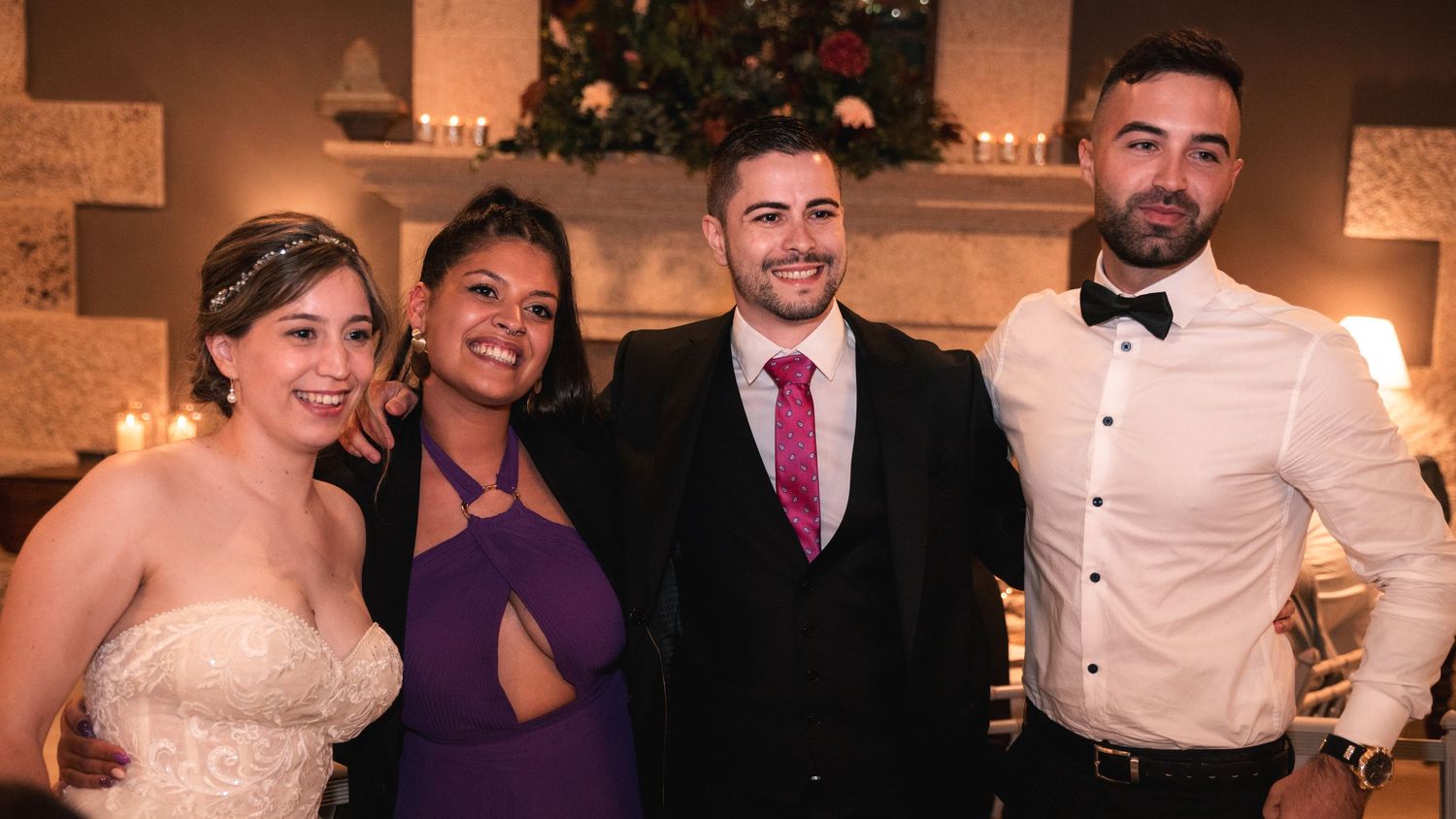 Wedding guests dancing and celebrating at a reception with festive lighting and decor in an elegant venue.
