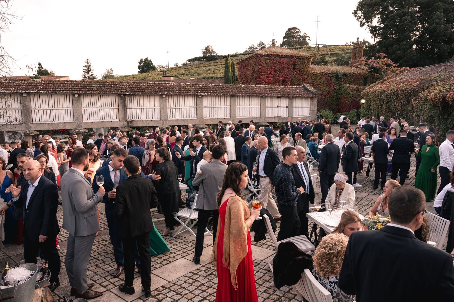 A large crowd of wedding guests gathered in an outdoor courtyard during a formal celebration event.