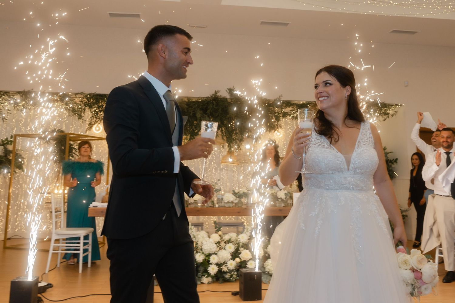 Sparklers illuminate a wedding reception dance floor as guests celebrate in an elegant indoor venue.