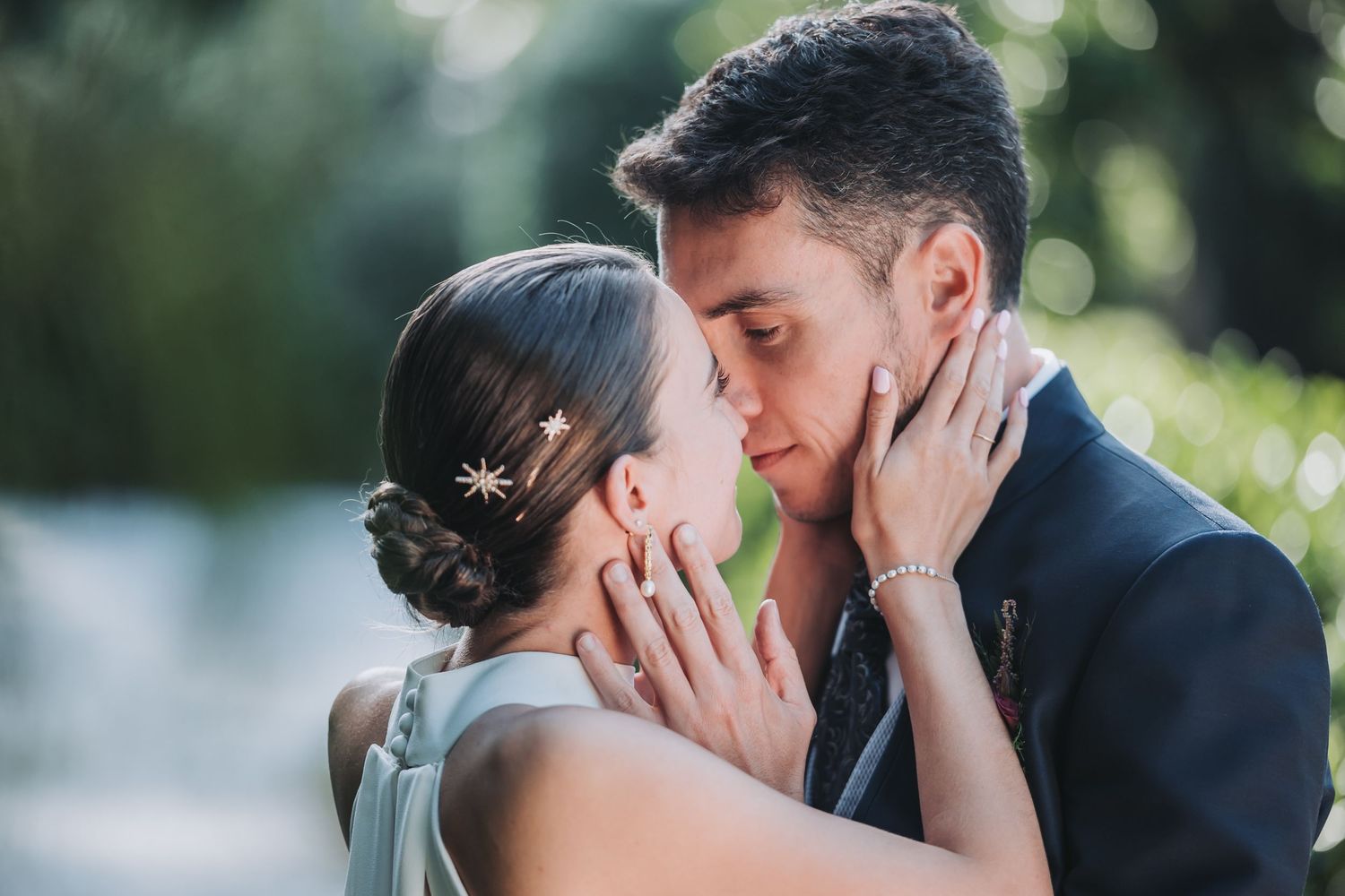 A romantic wedding couple shares tender moments in a garden setting with soft natural lighting and bokeh effects.