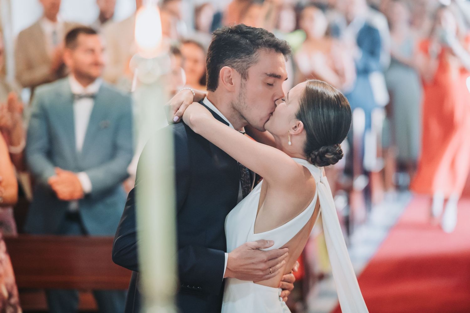 Newlyweds share an intimate moment during their wedding ceremony in a church with red carpet.