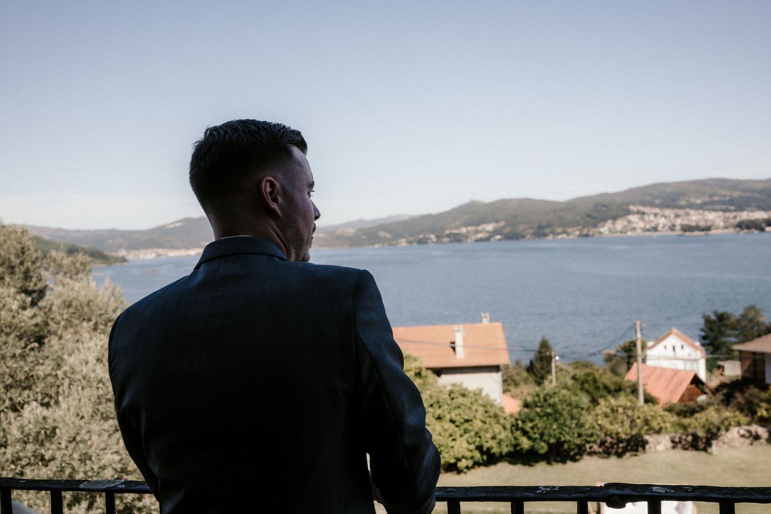 A scenic coastal view with buildings nestled along the hillside overlooking a tranquil bay on a sunny day.