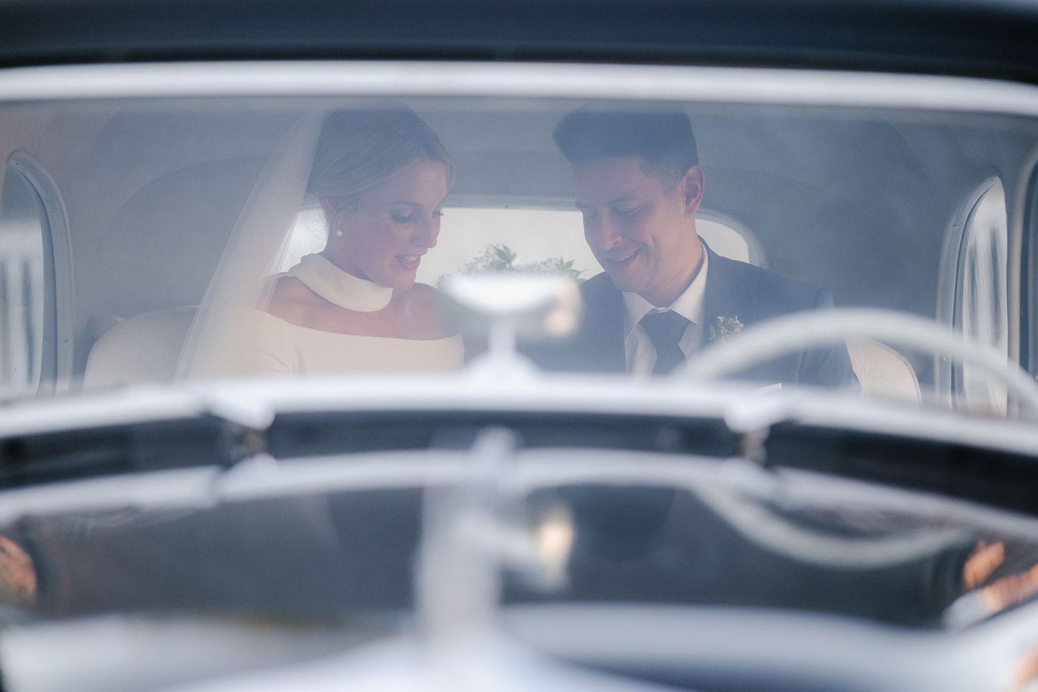 A couple sits together in a vintage car looking at a map during a road trip.