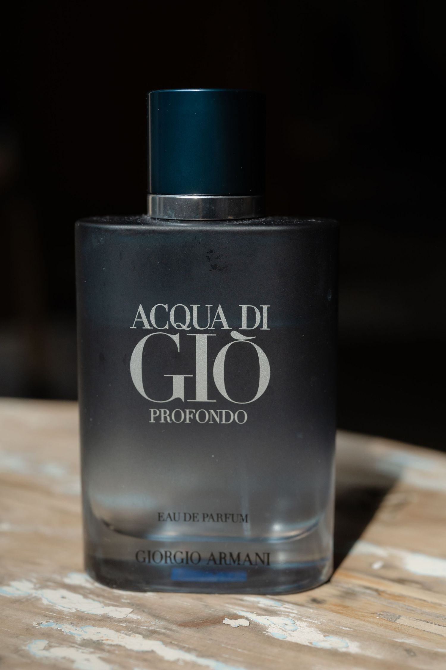 Multiple bottles of Giorgio Armani Acqua di Gio cologne arranged on a rustic wooden surface.