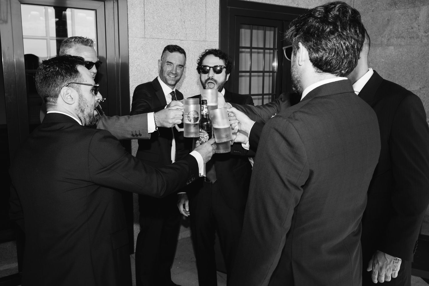 A black and white photograph shows a group of people in formal attire gathered at what appears to be a social event.
