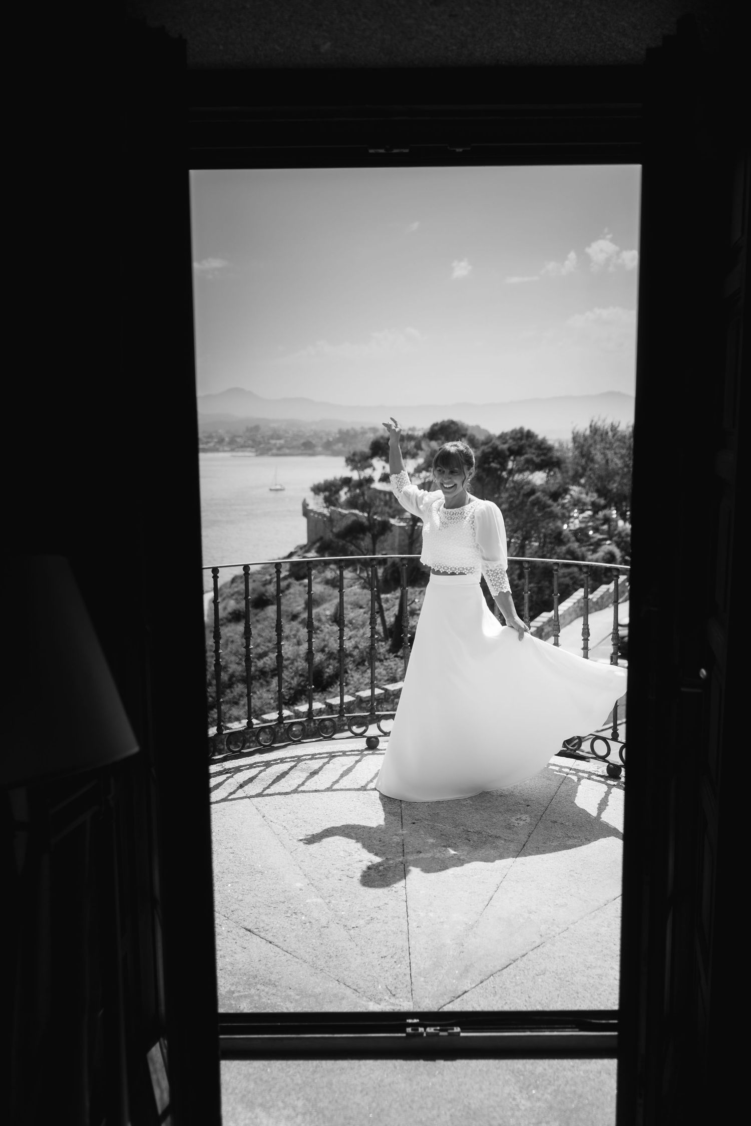 Black and white photograph of a wedding dress displayed on balcony with mountain view.