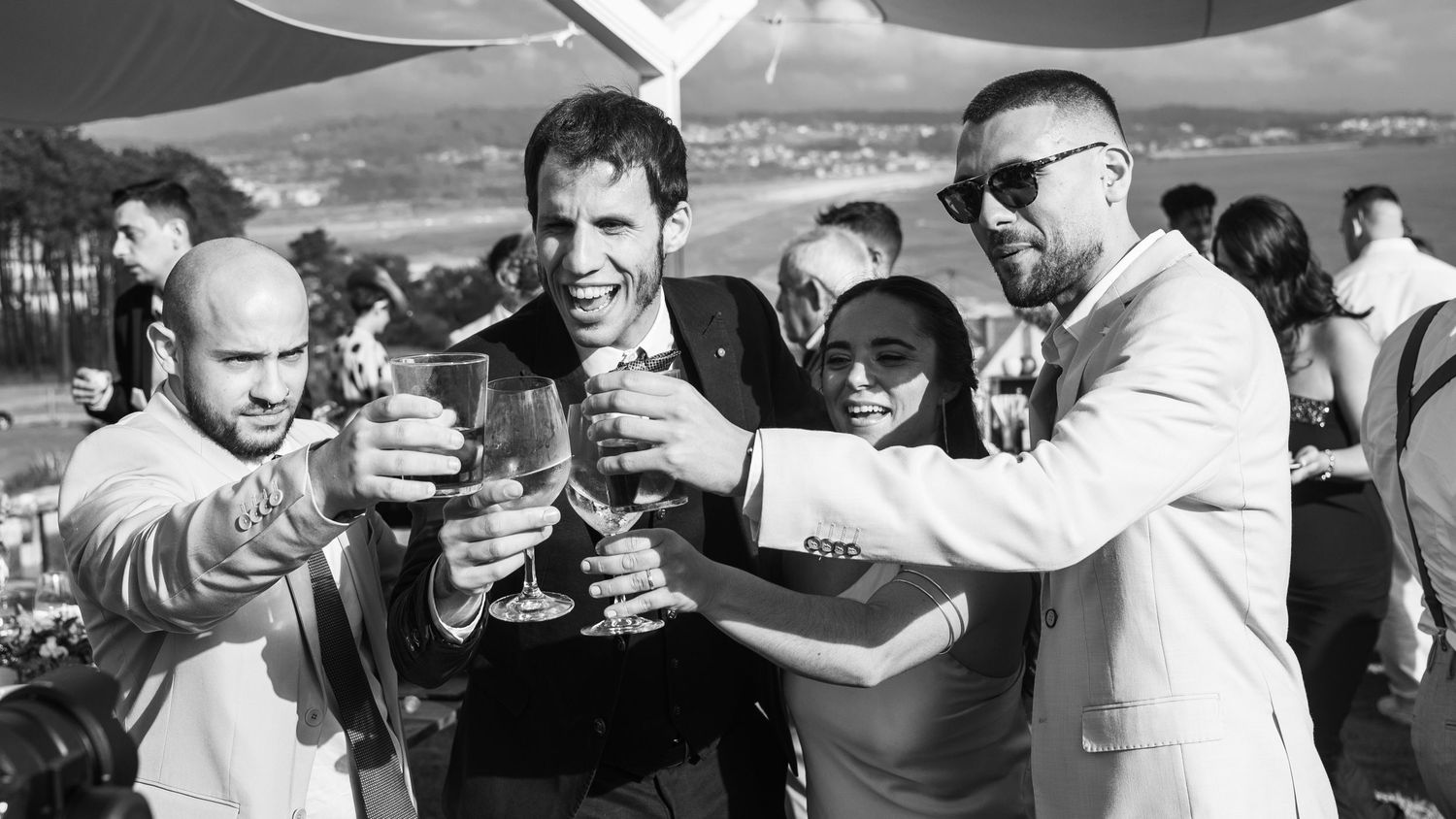 A group of people clinking beer glasses together in a celebratory toast at an outdoor gathering.