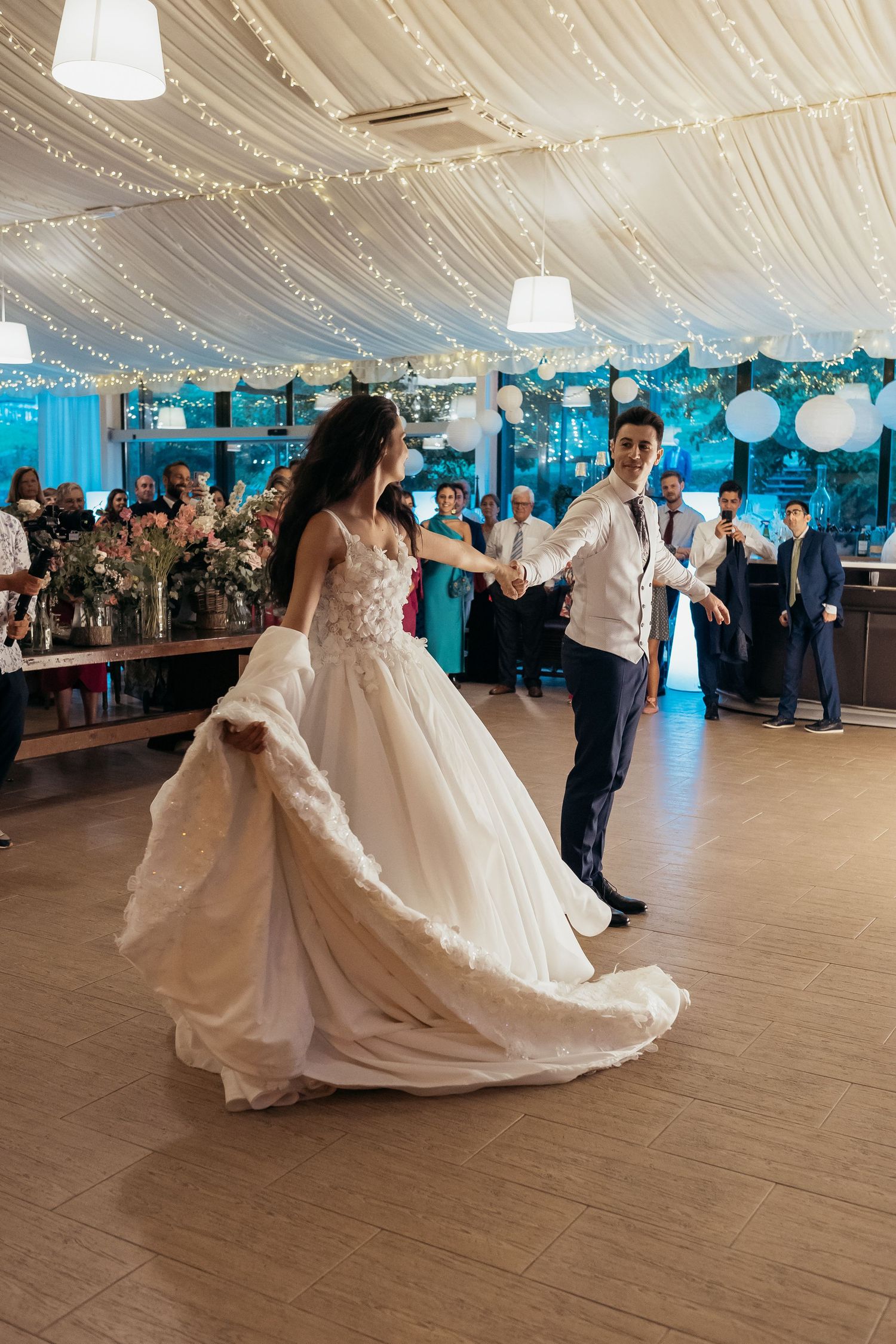 Wedding reception dance floor with elegant white tent draping and blue accent lighting.