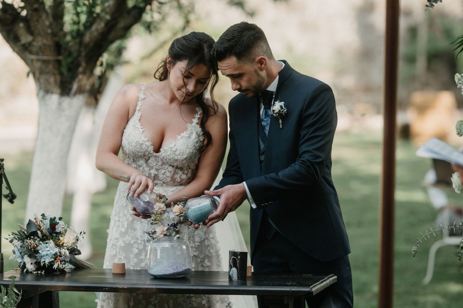 Couple in formal wedding attire shares a tender moment outdoors during a garden ceremony.