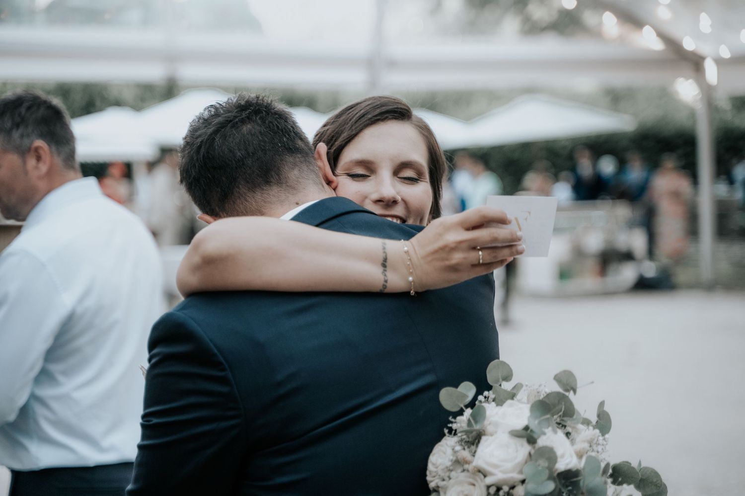 A couple embraces during an emotional moment at an outdoor wedding celebration.