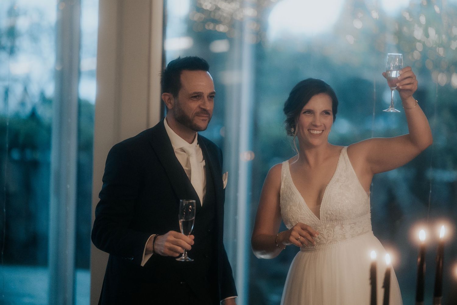 Newlyweds share a toast during an elegant evening reception with candlelit ambiance.