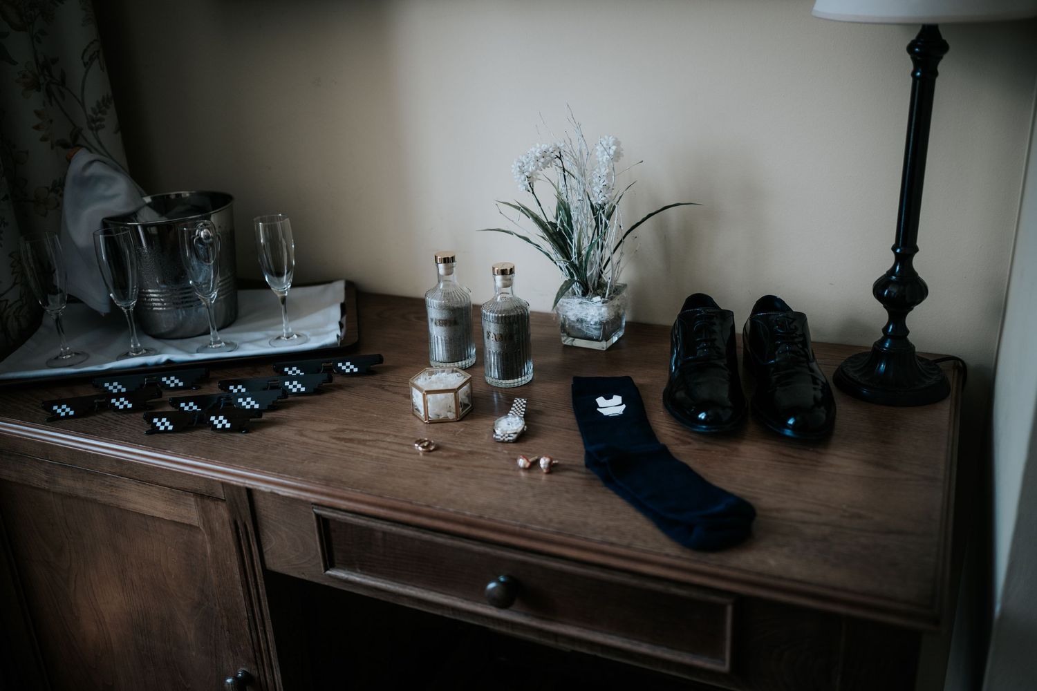 Vintage wooden table with lamp, glass, and decorative items in a dimly lit room.