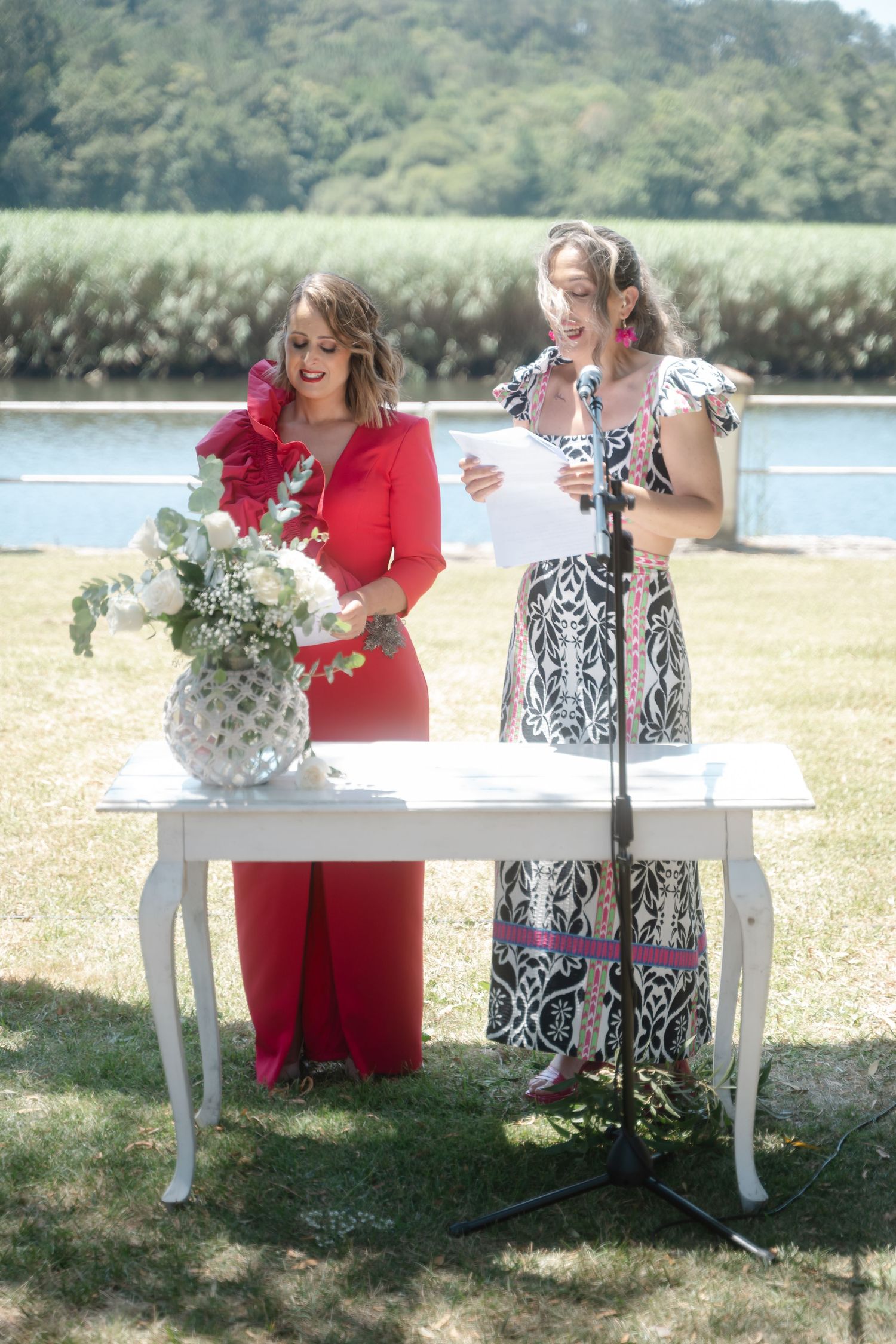 Wedding ceremony setup with white chairs and tables arranged outdoors near a waterfront.