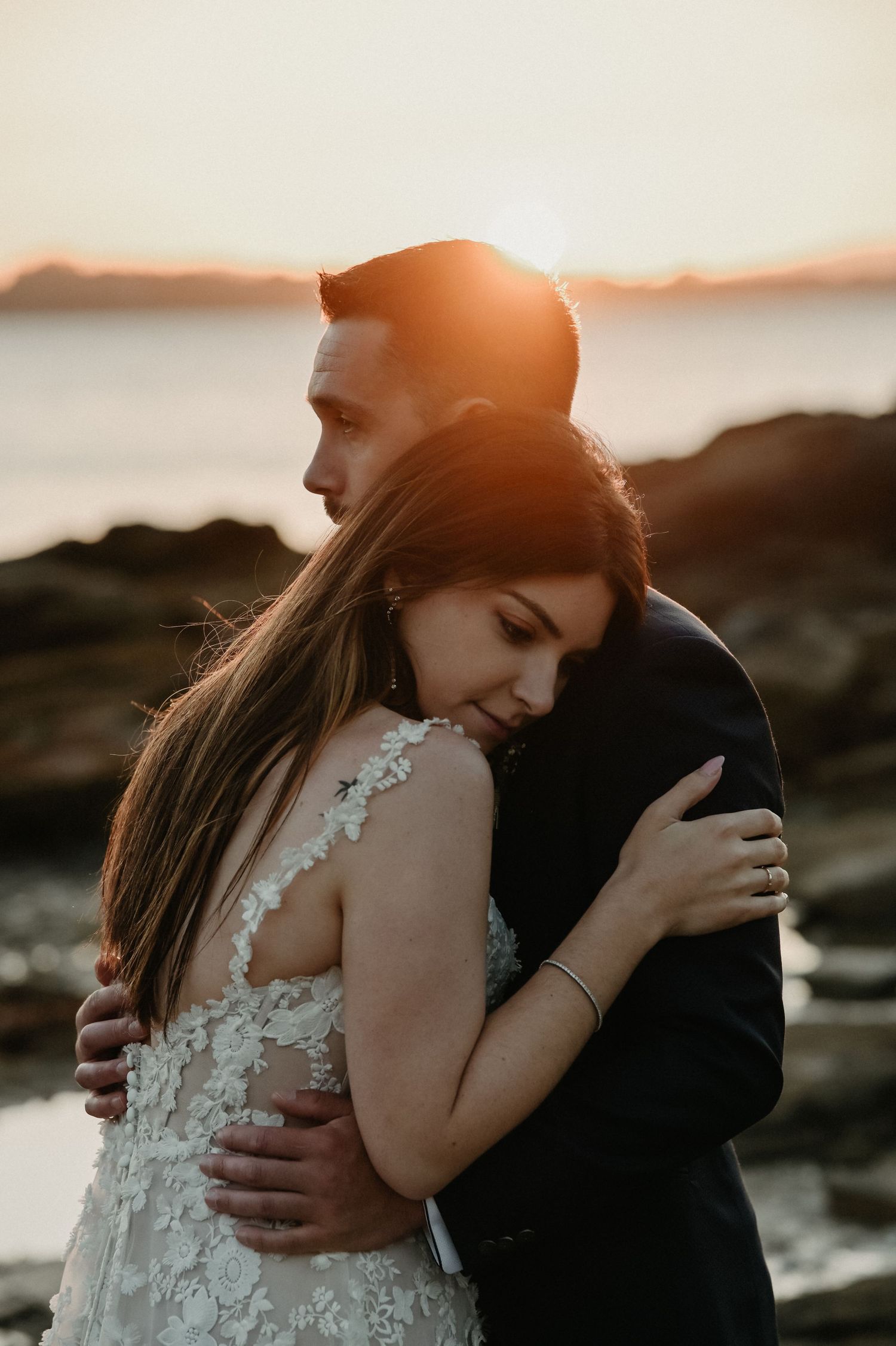 A romantic sunset beach photoshoot featuring a couple in wedding attire embracing.