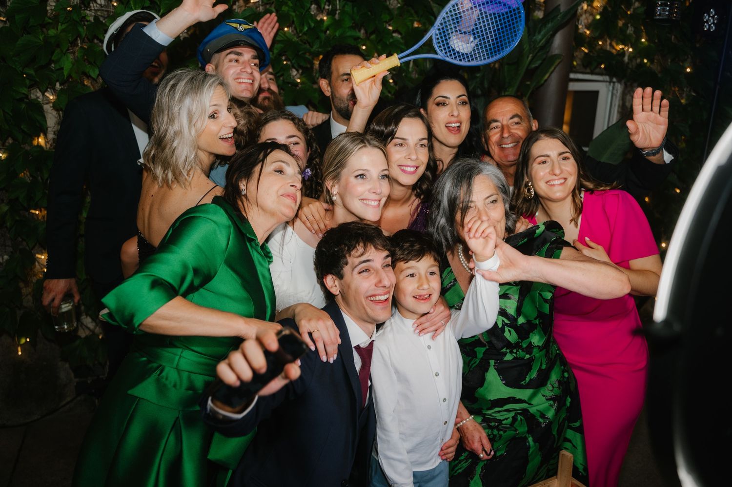 Large group of wedding guests pose enthusiastically together for a fun party photo.