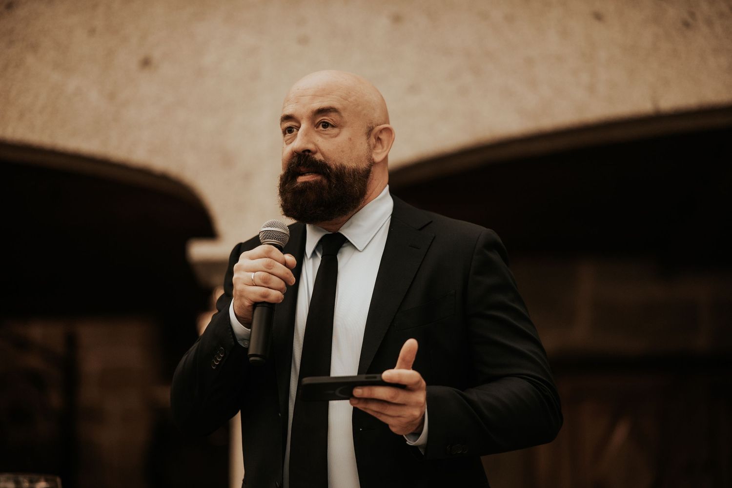 A series of candid black and white photos showing a person in formal attire speaking into a microphone.