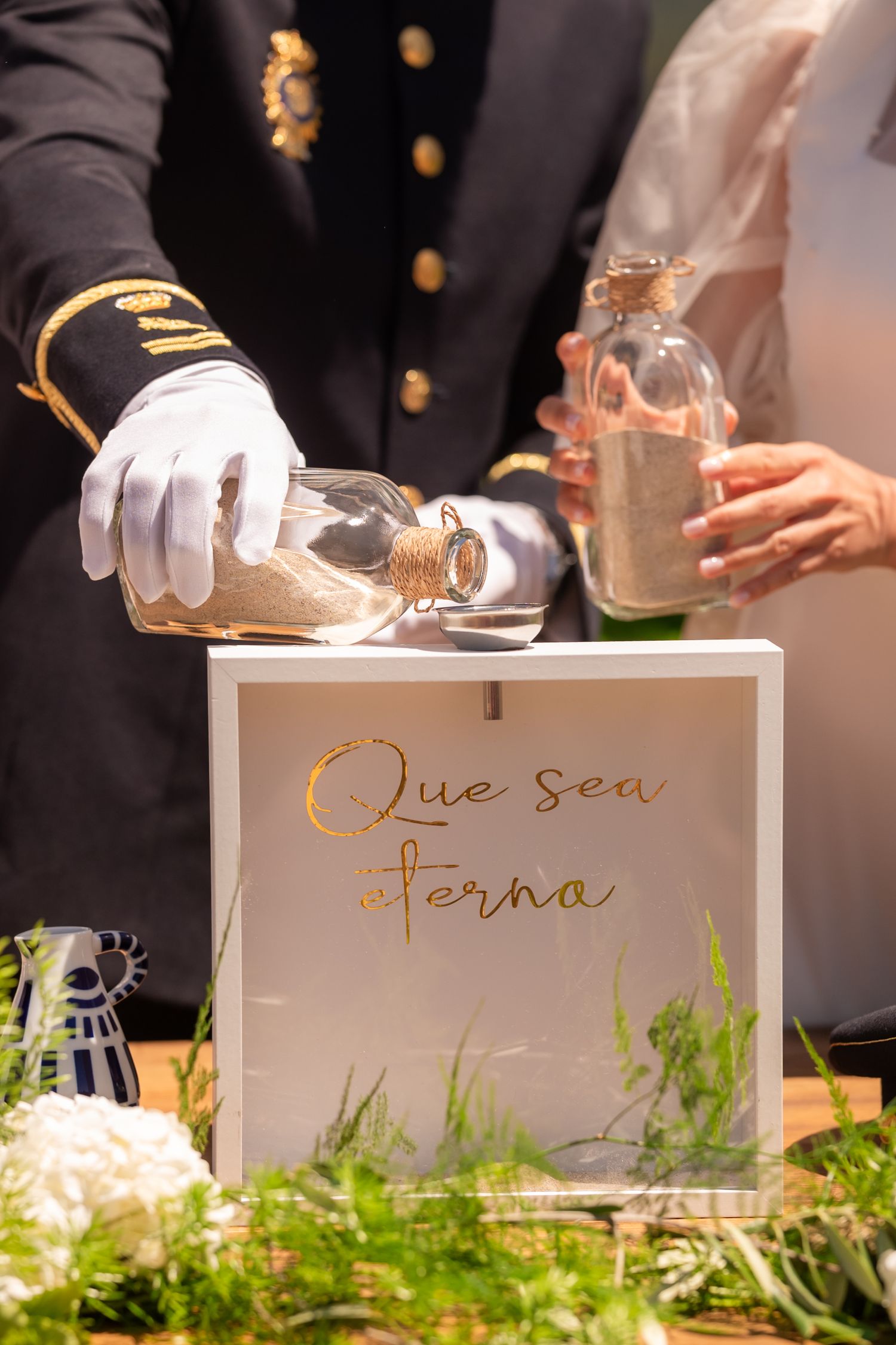 White decorative boxes with text arranged on a table with greenery and soft lighting at an event.
