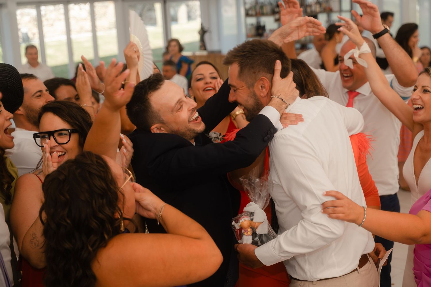 Wedding guests dance and celebrate on a crowded dance floor at a lively reception party.