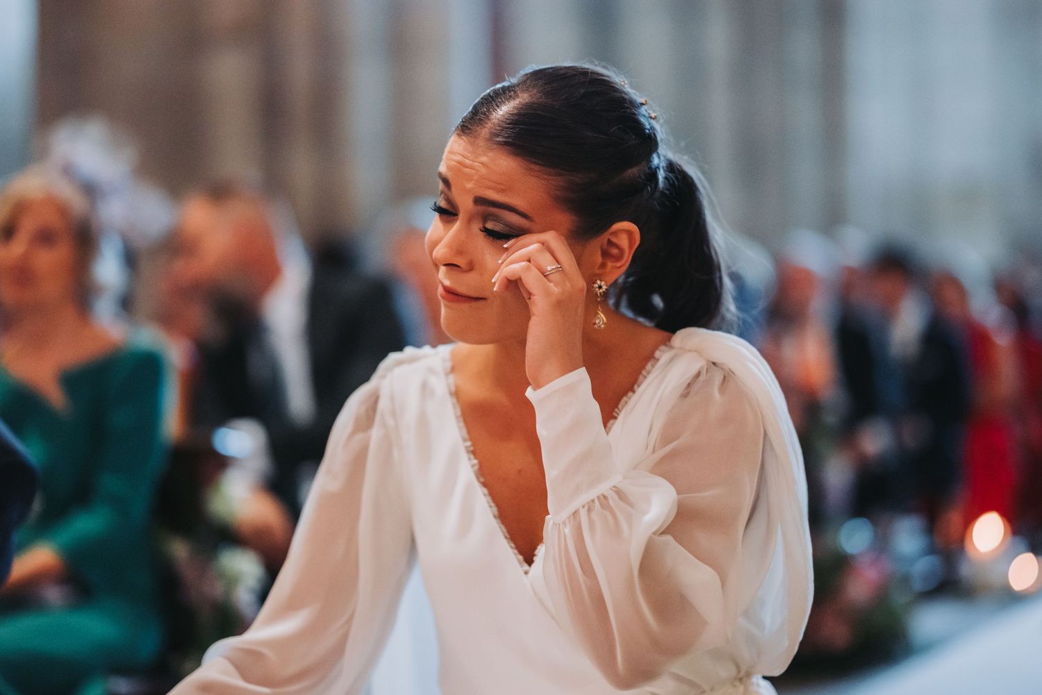A bride in a white dress sits at a table during a wedding reception.