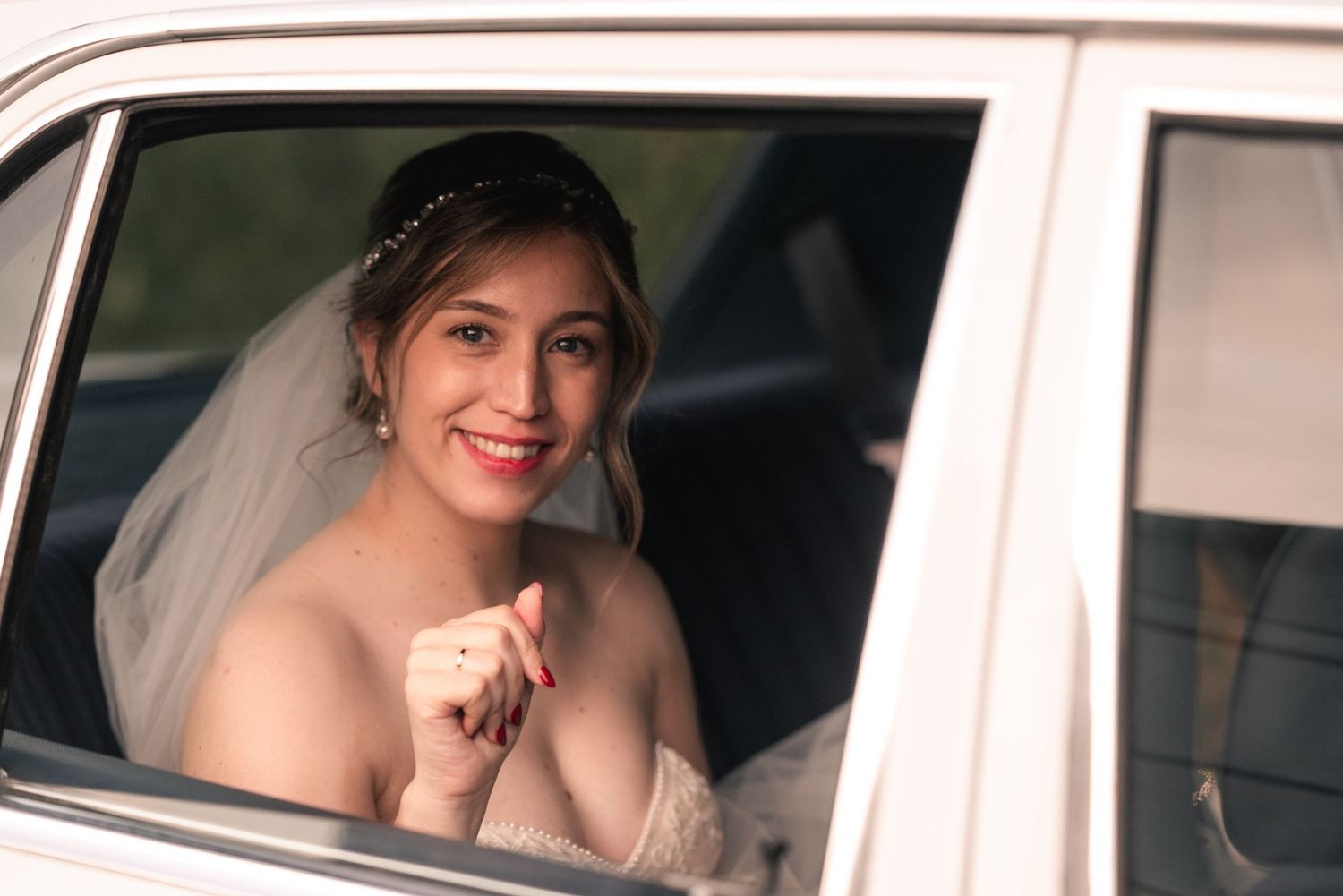 A wedding car scene showing a bride in a white dress sitting in an elegant vehicle.