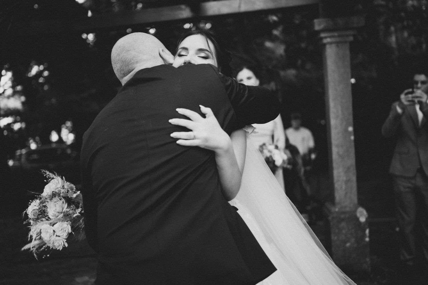Black and white wedding photos showing emotional moments and embraces during a celebration.