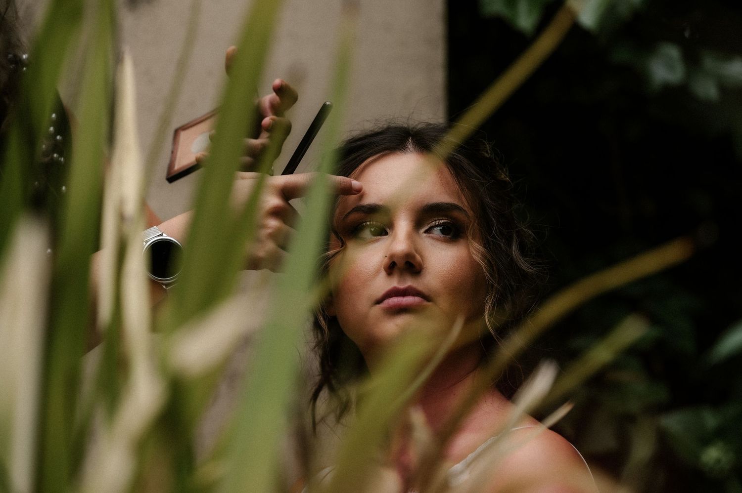 A person looks up at the sky through tree branches in a contemplative outdoor portrait.