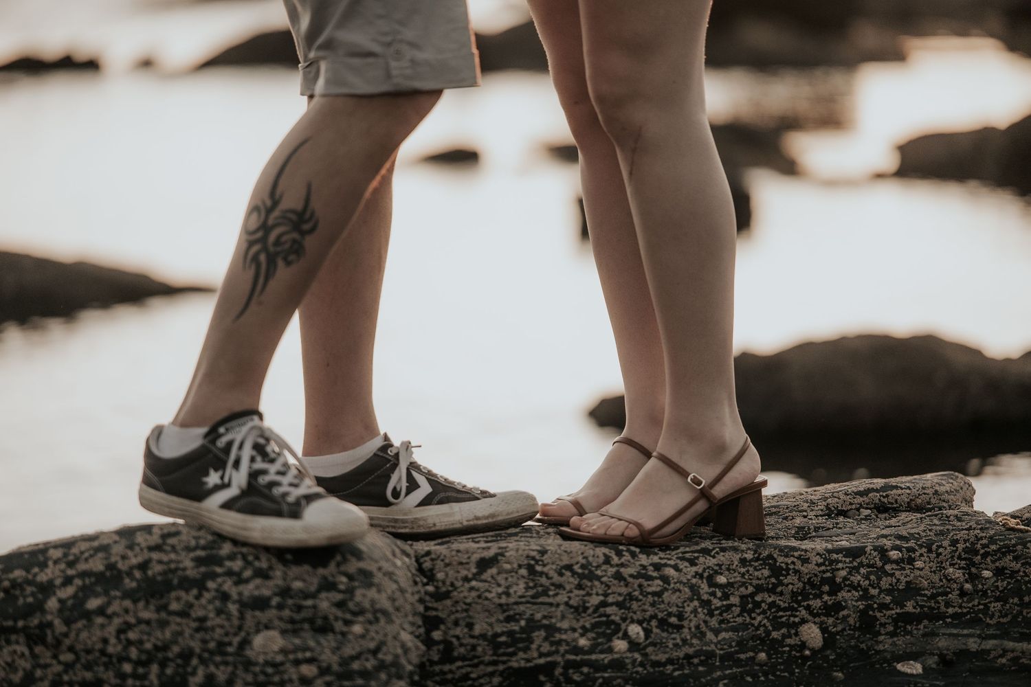 Close-up view of feet walking on rocky terrain in casual shoes, shown in a sepia-toned photographic style.
