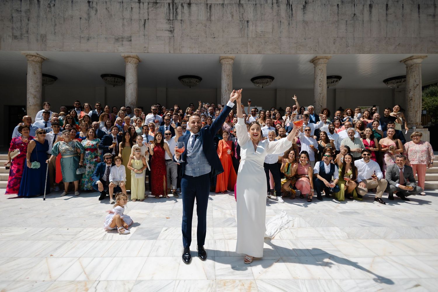 Wedding guests stand in formation for a group photo on snow-covered ground during a winter celebration.