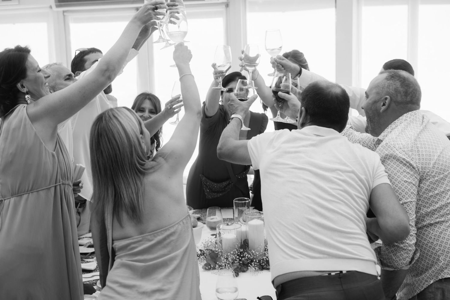 Wedding guests dancing and celebrating with raised arms in a joyful group dance formation.
