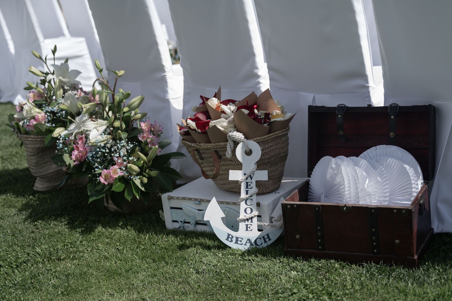White candles in glass holders illuminate elegant floral arrangements and decorative elements at an outdoor wedding setting.