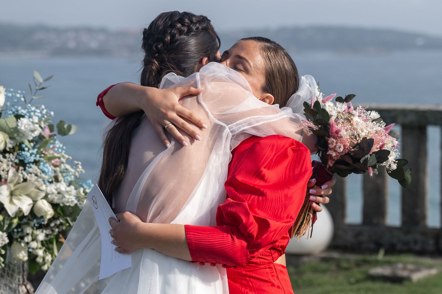 Wedding guests embrace in a series of candid moments against a scenic waterfront backdrop.
