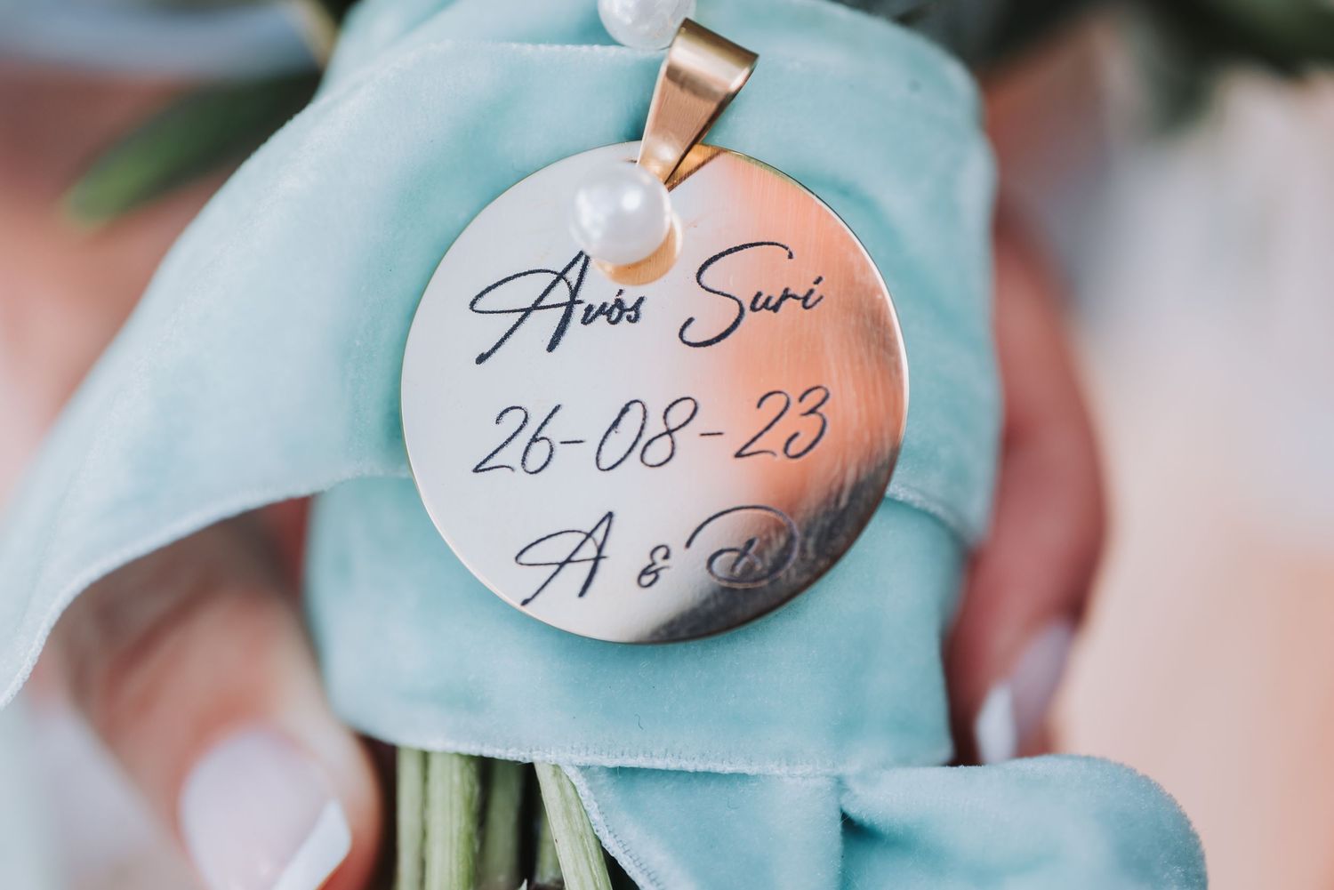 Wedding invitation cards with handwritten details rest on a soft turquoise fabric surface.