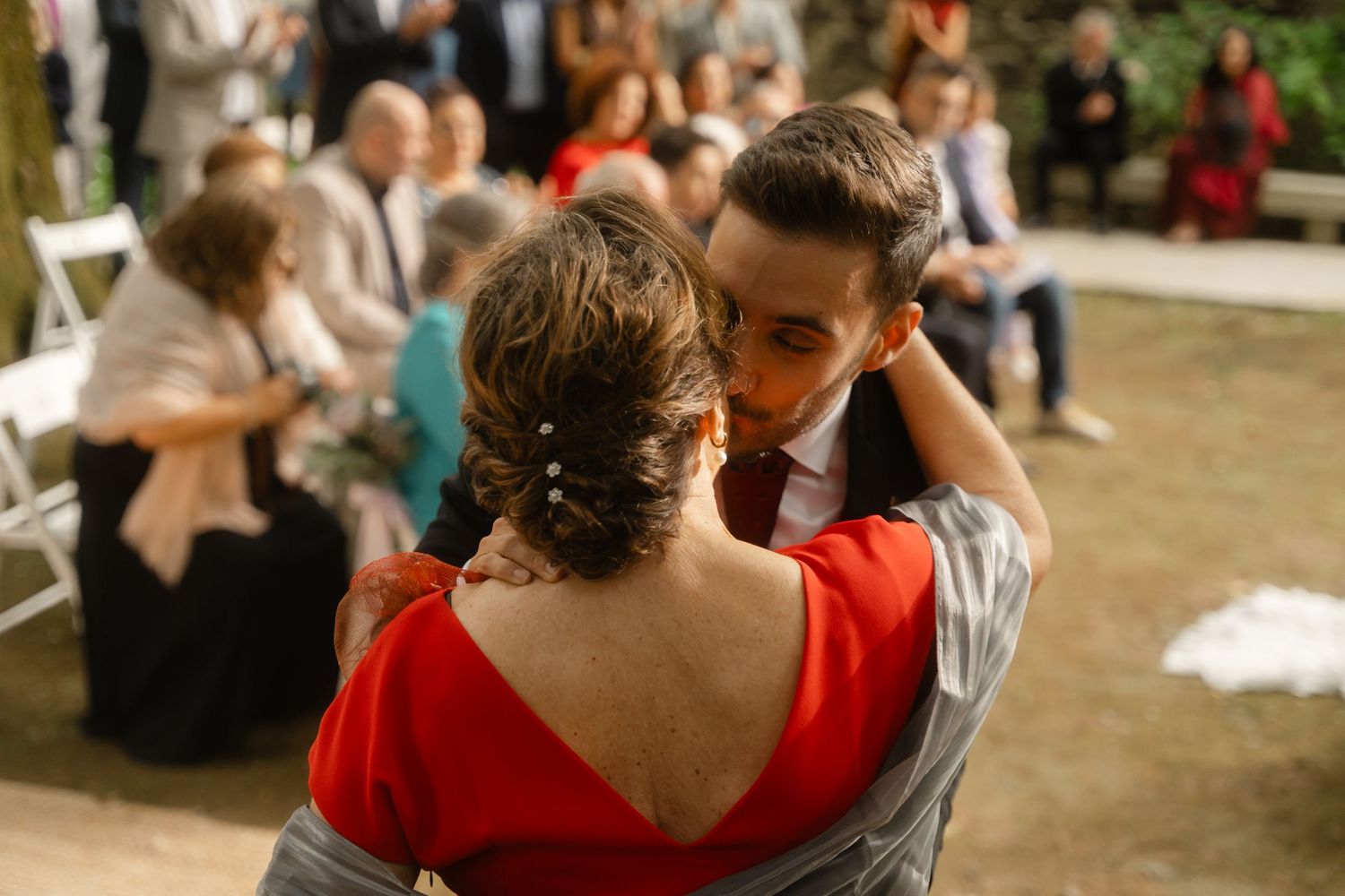 Wedding reception guests socializing outdoors with vibrant red accents in the scene.