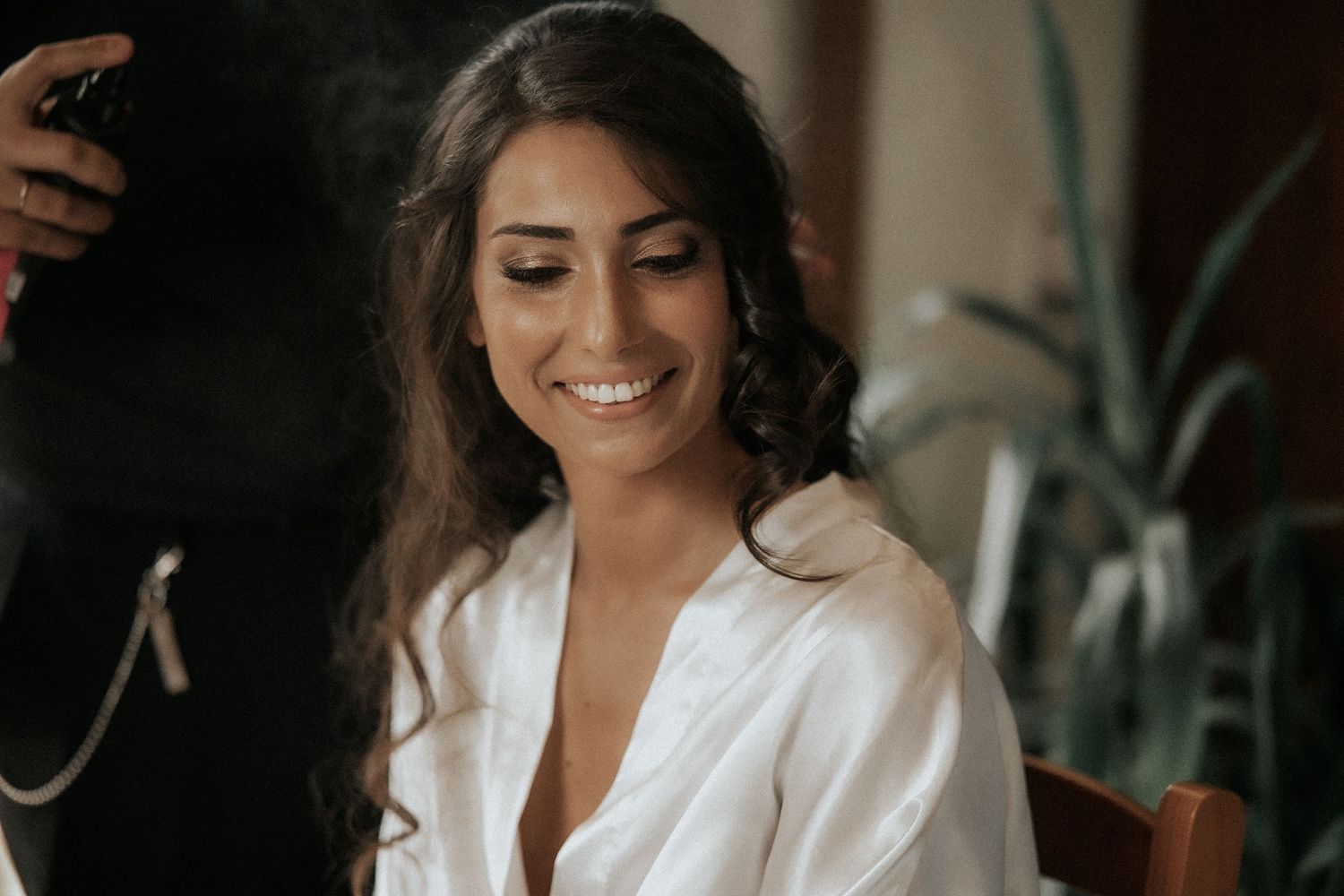 A bride in a white wedding dress gets ready for her special day in a dimly lit room.
