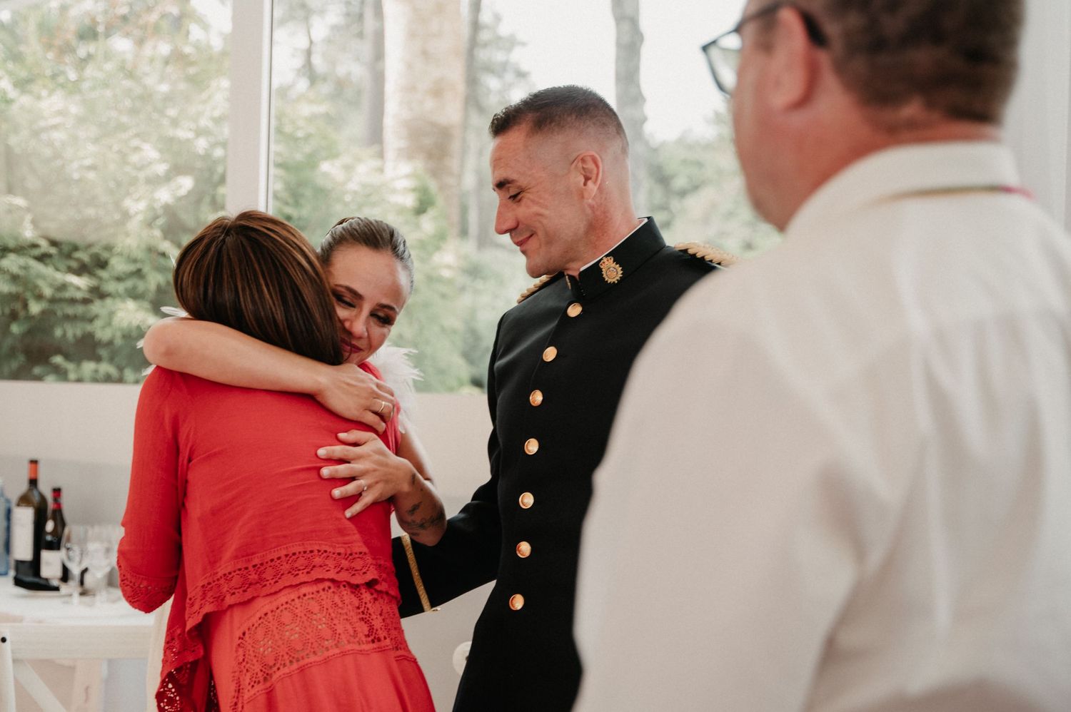 Wedding guests in formal attire gather around decorated reception tables during a celebration.