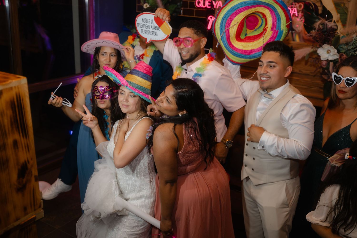 Wedding party guests dancing with colorful props and accessories at a festive reception celebration.
