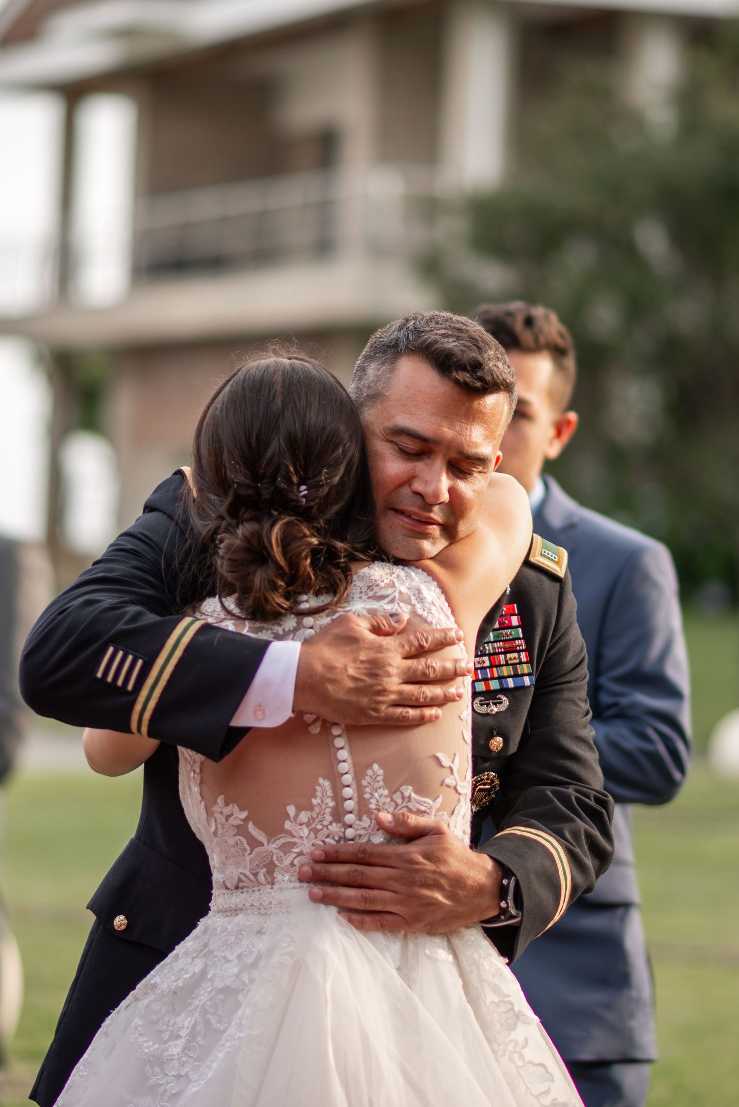 Military service member dips partner in white wedding dress during romantic outdoor dance.