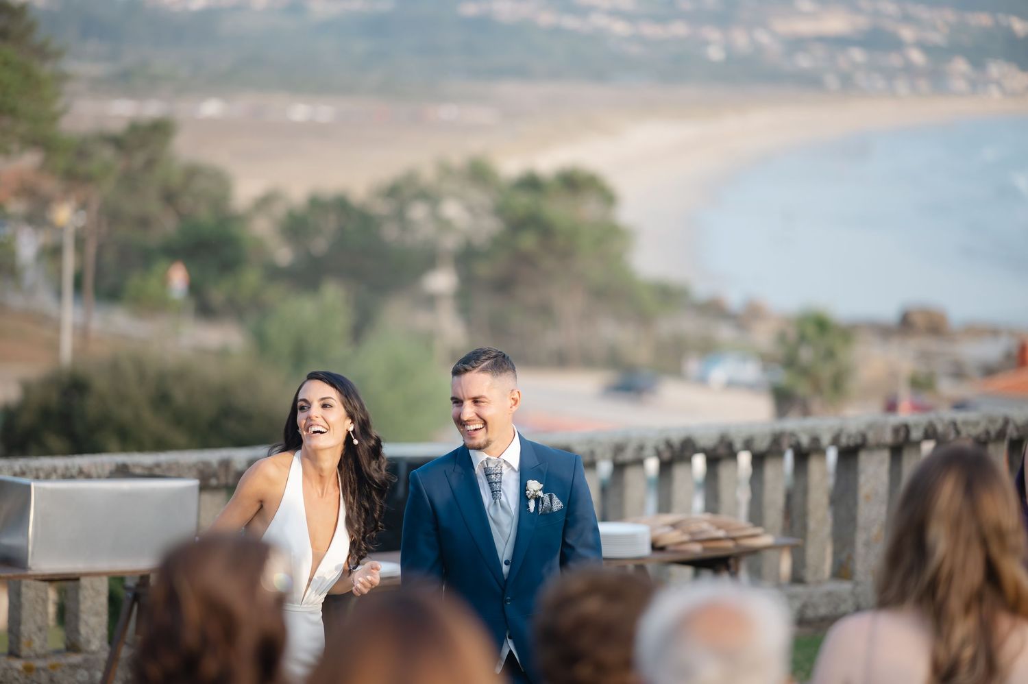 Wedding couple and guests celebrate during outdoor ceremony with mountain views and wooden fence in background.