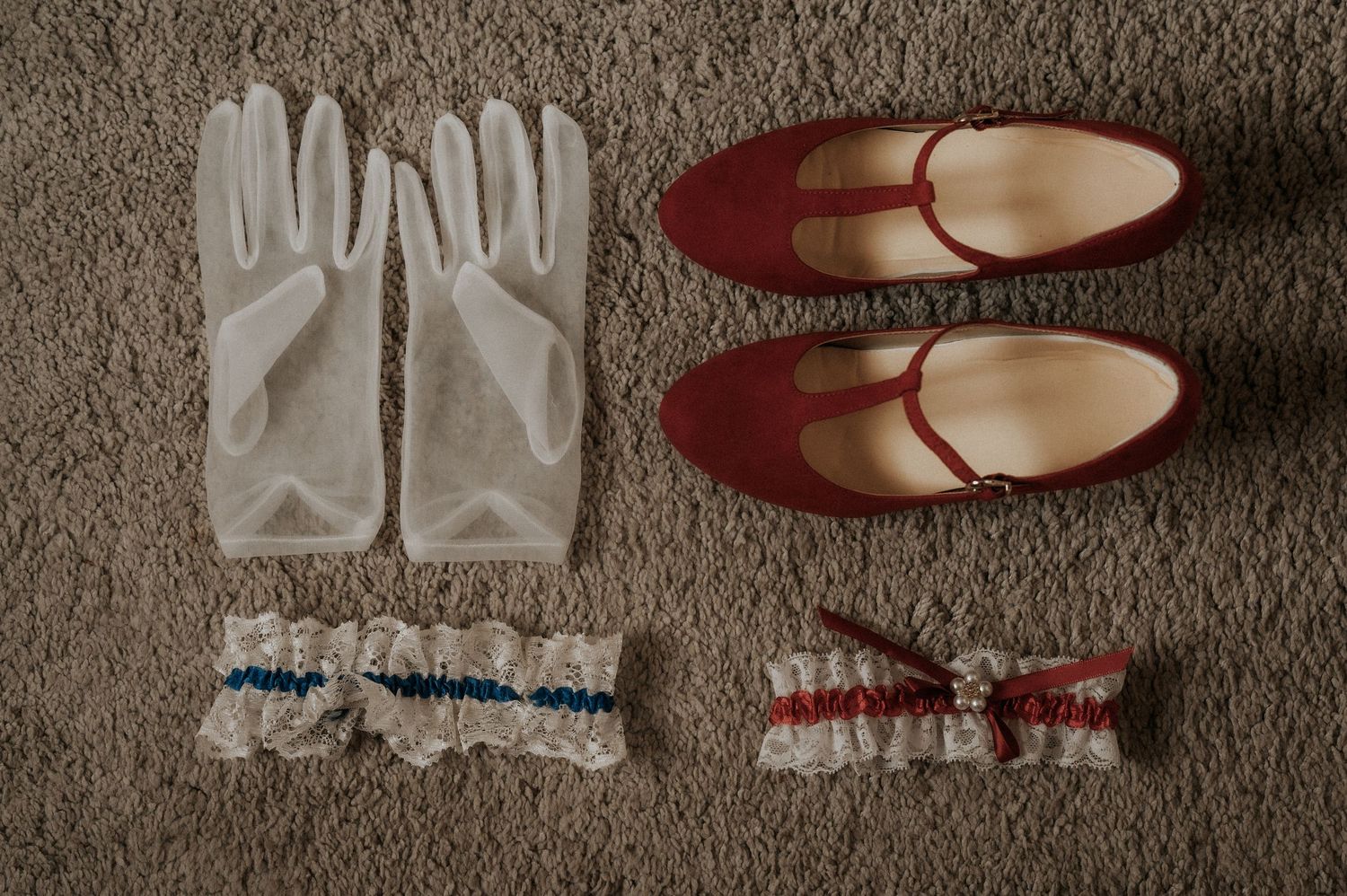 White ballet slippers and red pointe shoes arranged in a line on a dark textured surface.