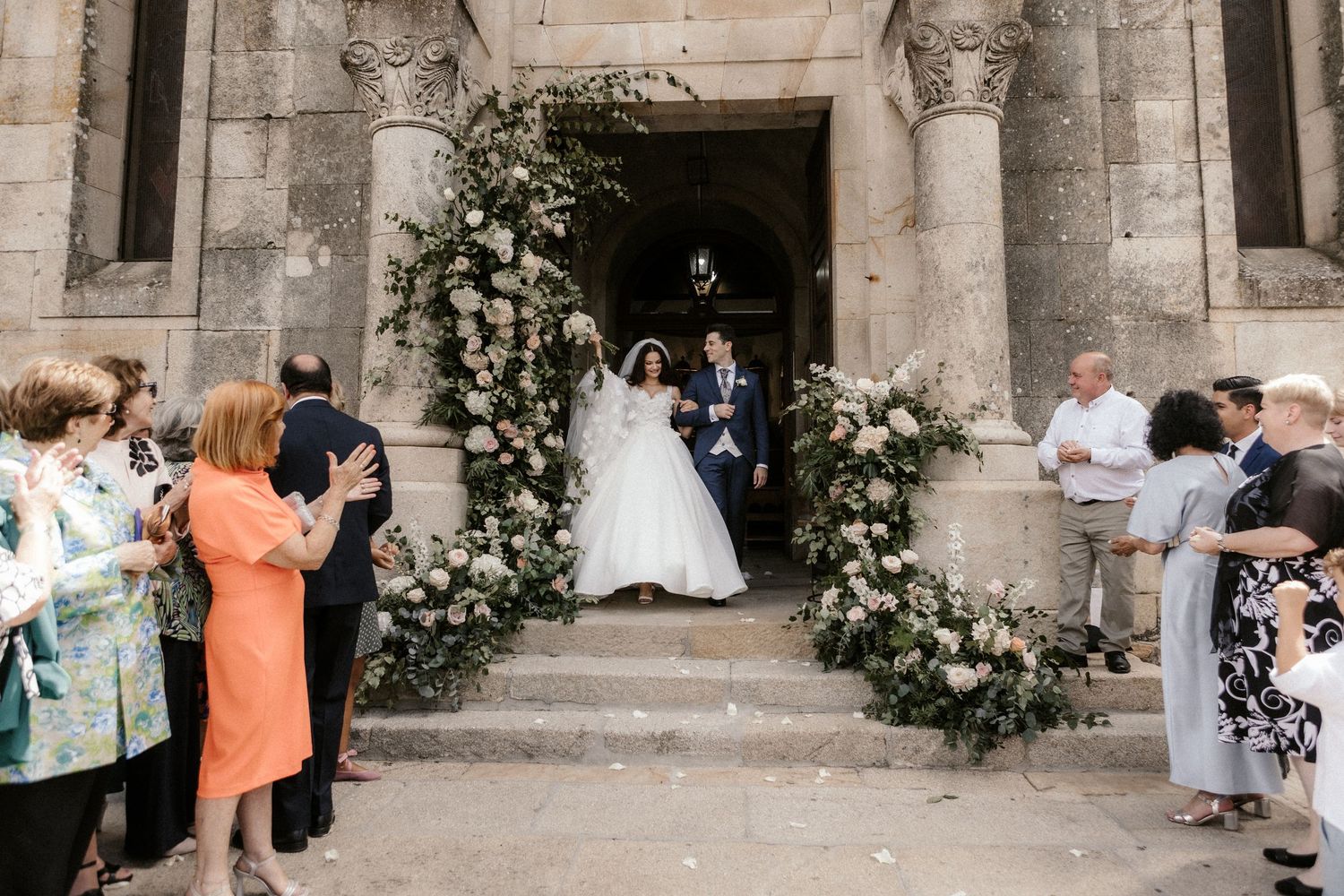 Church entrance adorned with floral arch decorations as wedding guests gather on the stone steps.
