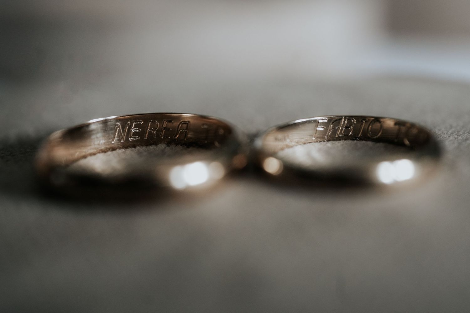 Close-up macro photography of gold wedding rings with shallow depth of field and bokeh effect.