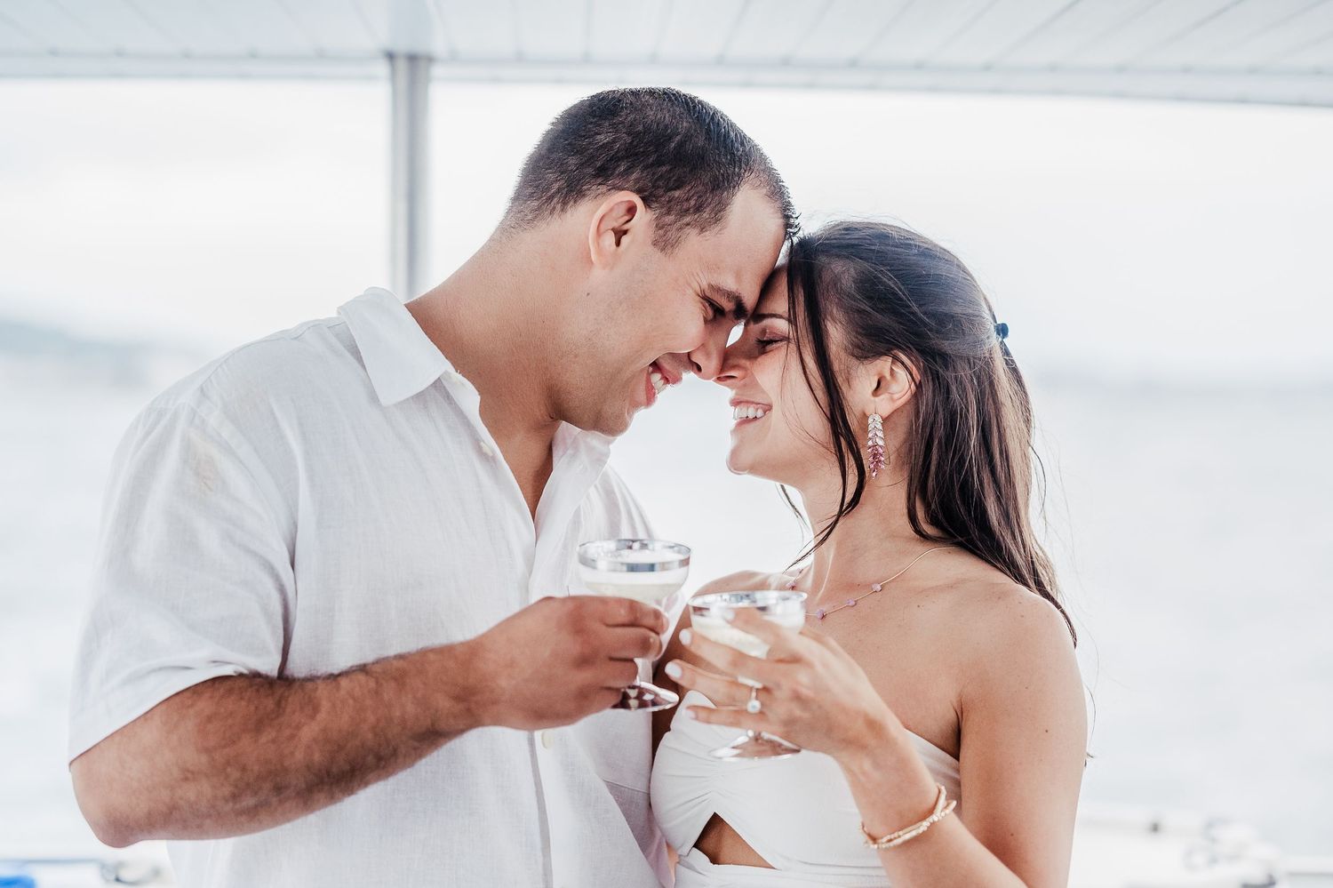 Romantic couple sharing an intimate moment while toasting with champagne glasses on a boat.