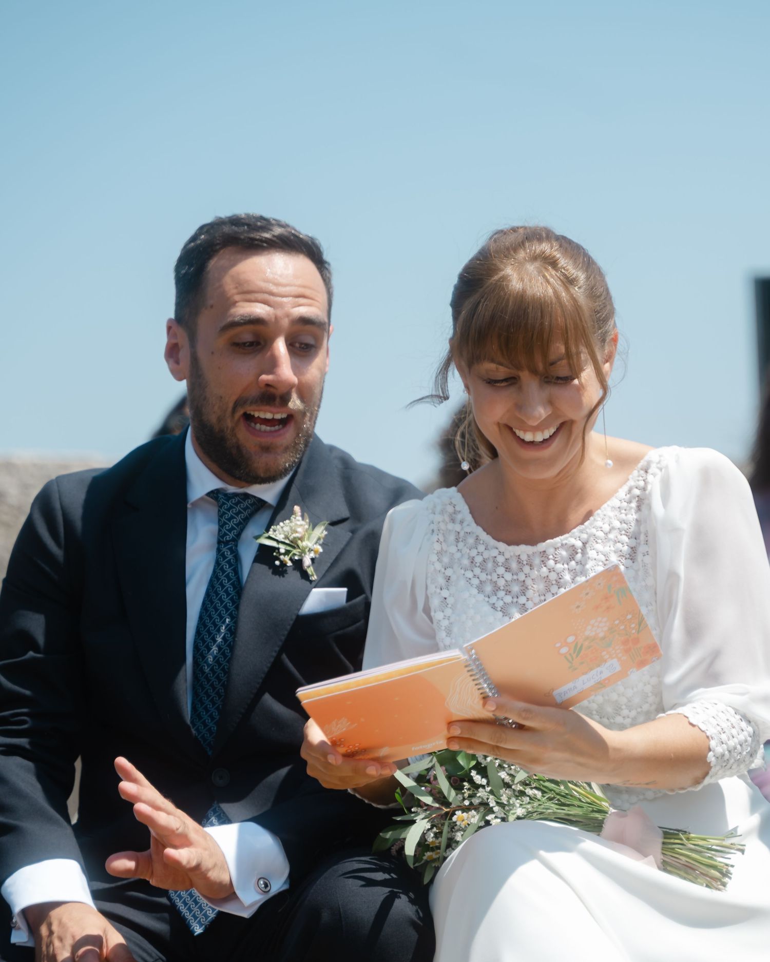 Wedding guests sharing joyful moments while seated outdoors at a ceremony.