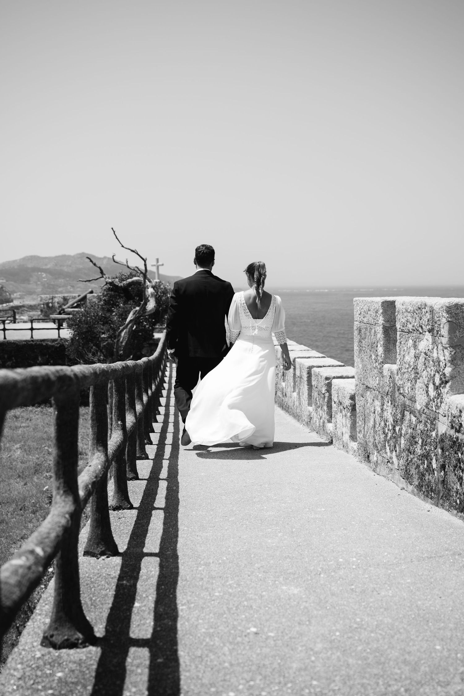 Black and white sequence of a bride and groom walking along a stone wall with their shadows casting dramatic silhouettes.