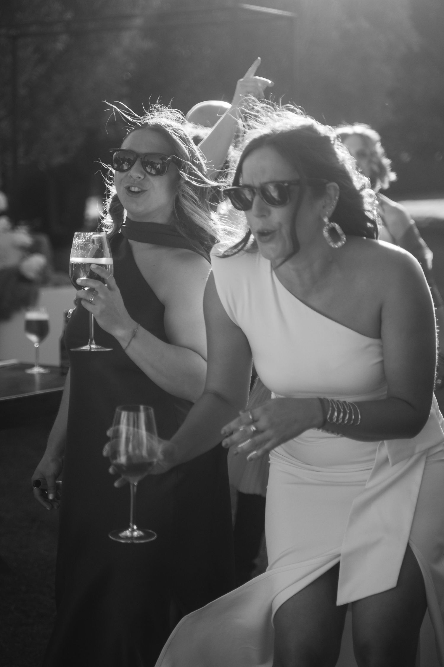 Black and white photo series shows a couple sharing drinks and intimate moments at an outdoor evening celebration.