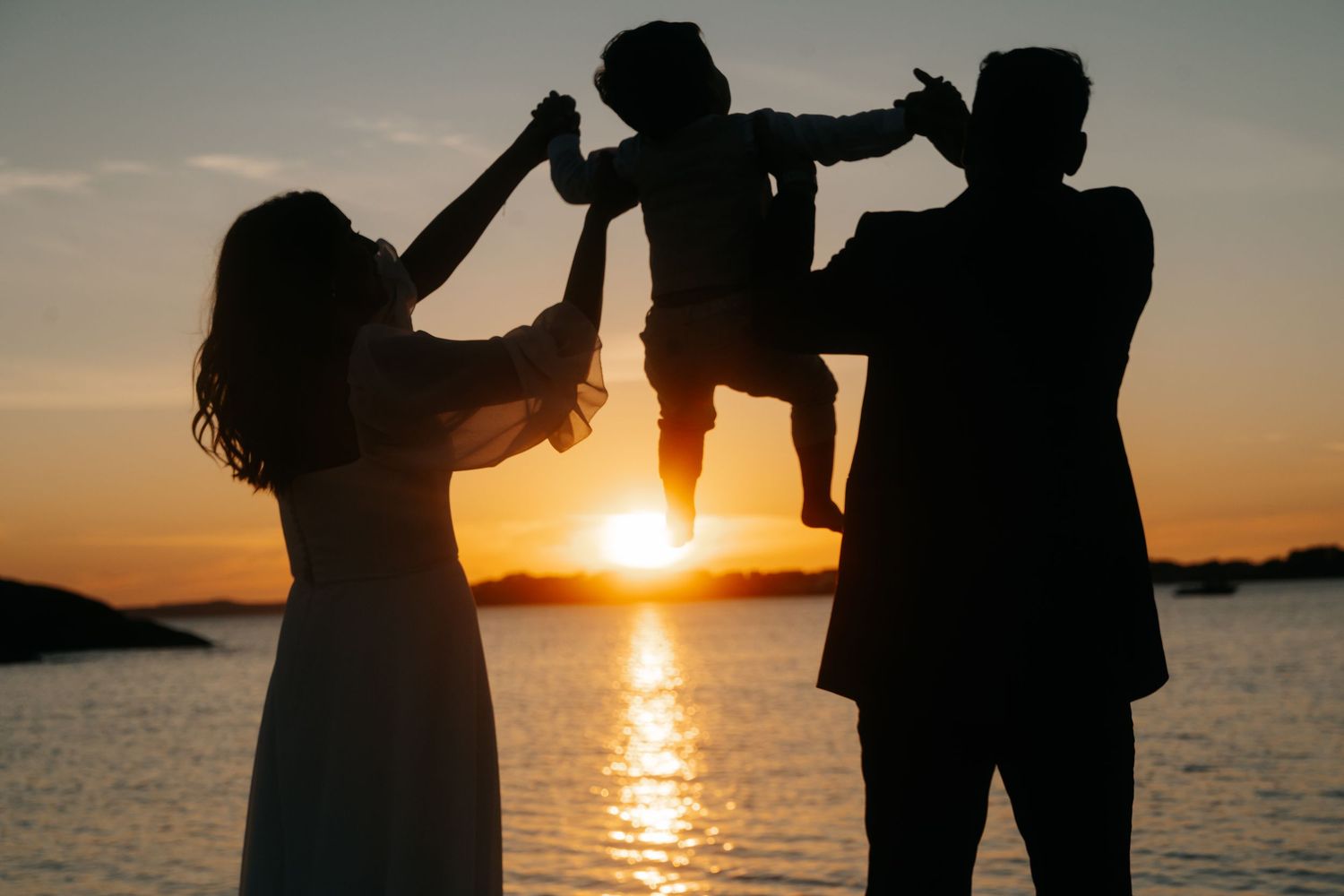 Silhouettes of couple dancing on beach at sunset with ocean waves in background.
