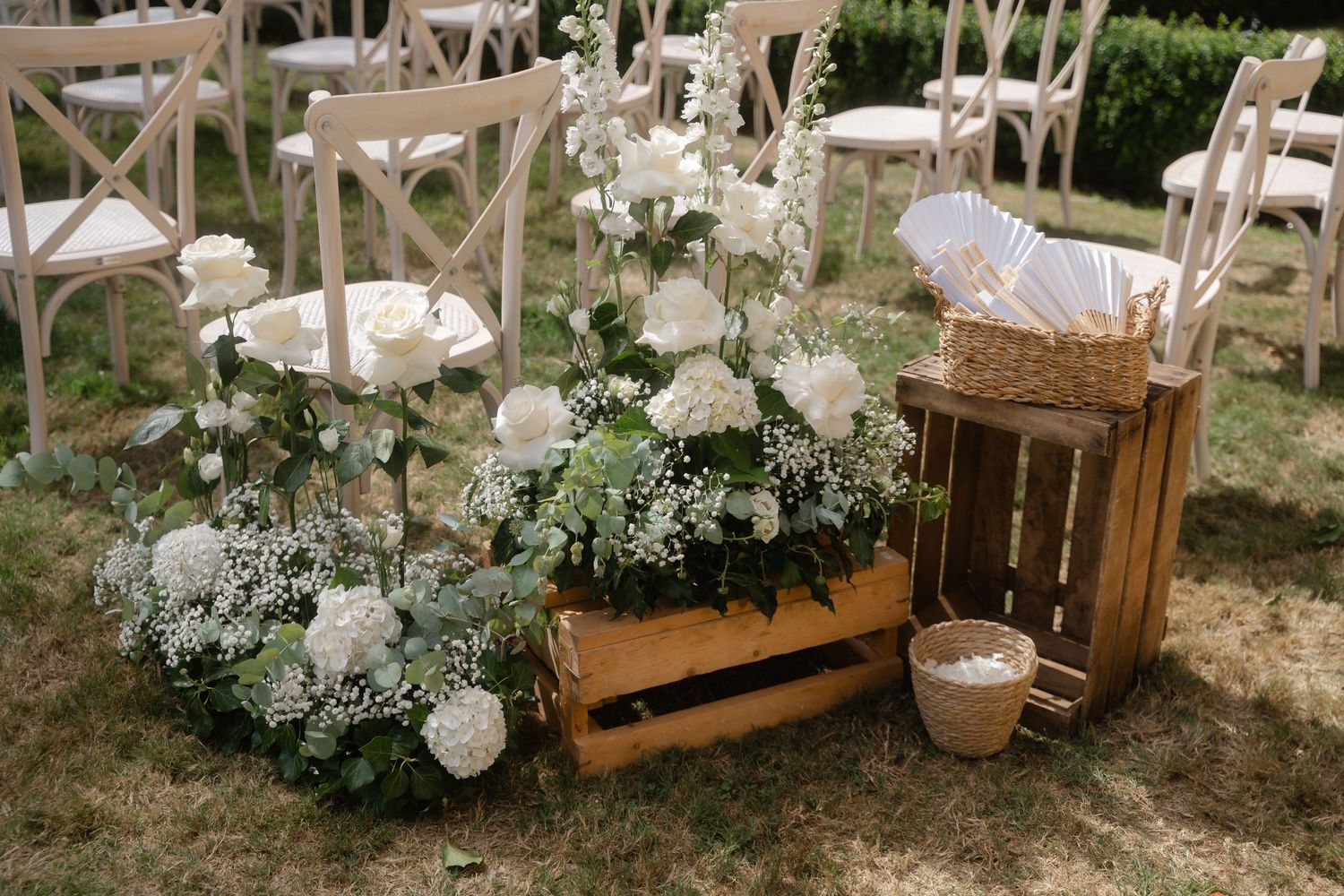 Rustic wooden crates and white floral arrangements create an elegant outdoor garden wedding display.